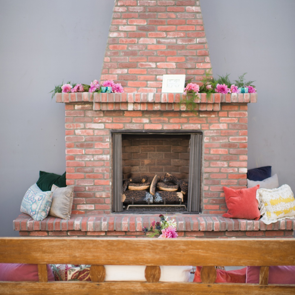 A brick fireplace and a wooden couch across from the fireplace
