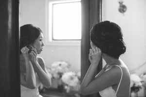 A bride putting on their earring in front of a mirror