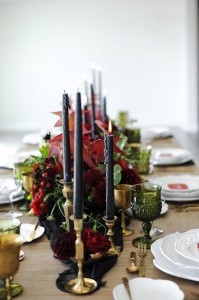 A close up image of a table's centerpiece and lit, black candles