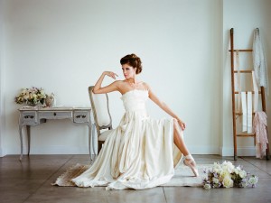 A bride posing in a chair while pointing their ballet shoe