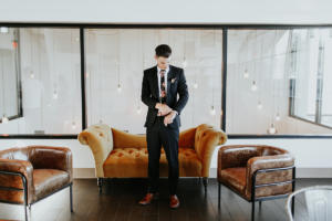 A person fixing their suit's sleeve in front of an elegant couch